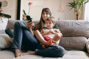 Son and mother watching tv together while sitting on couch