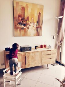 Toddler standing on white chair beside sideboard